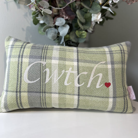 Plaid pillow with 'Cwtch' and a heart on a neutral background
