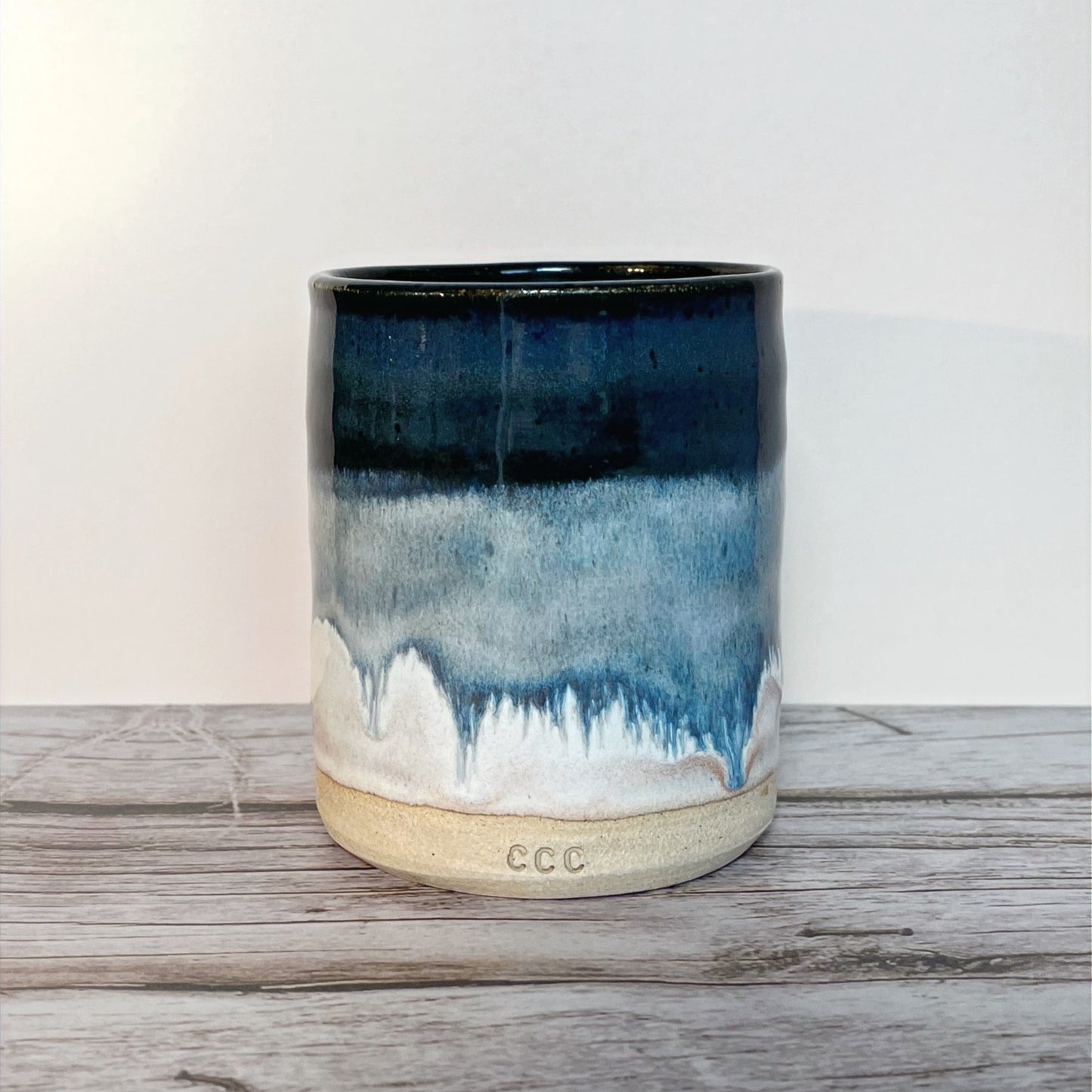 A refillable candle in a blue and white layered ceramic pot featuring a decorative wave pattern.