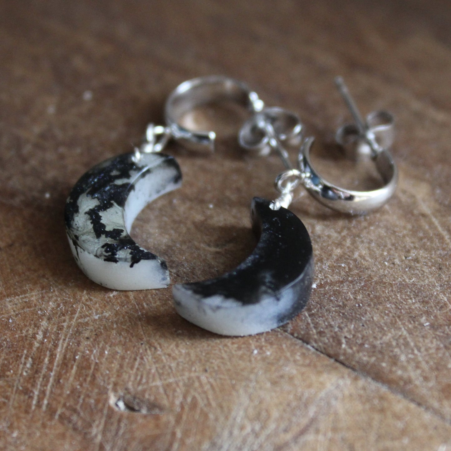 Pair of moon-shaped earrings on a wooden surface