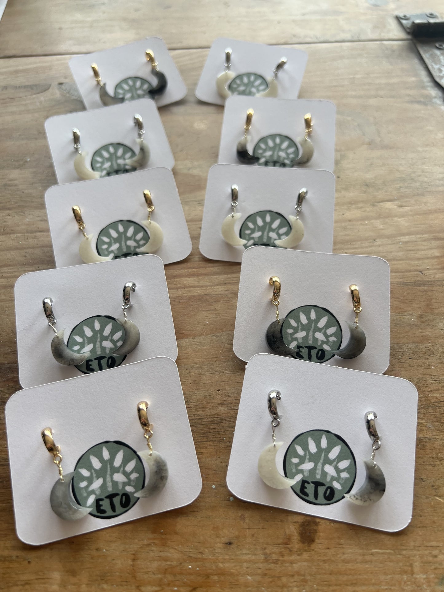 Set of gold and silver moon shaped earrings on display cards on a wooden surface. Perfect unique accessory for gifts.