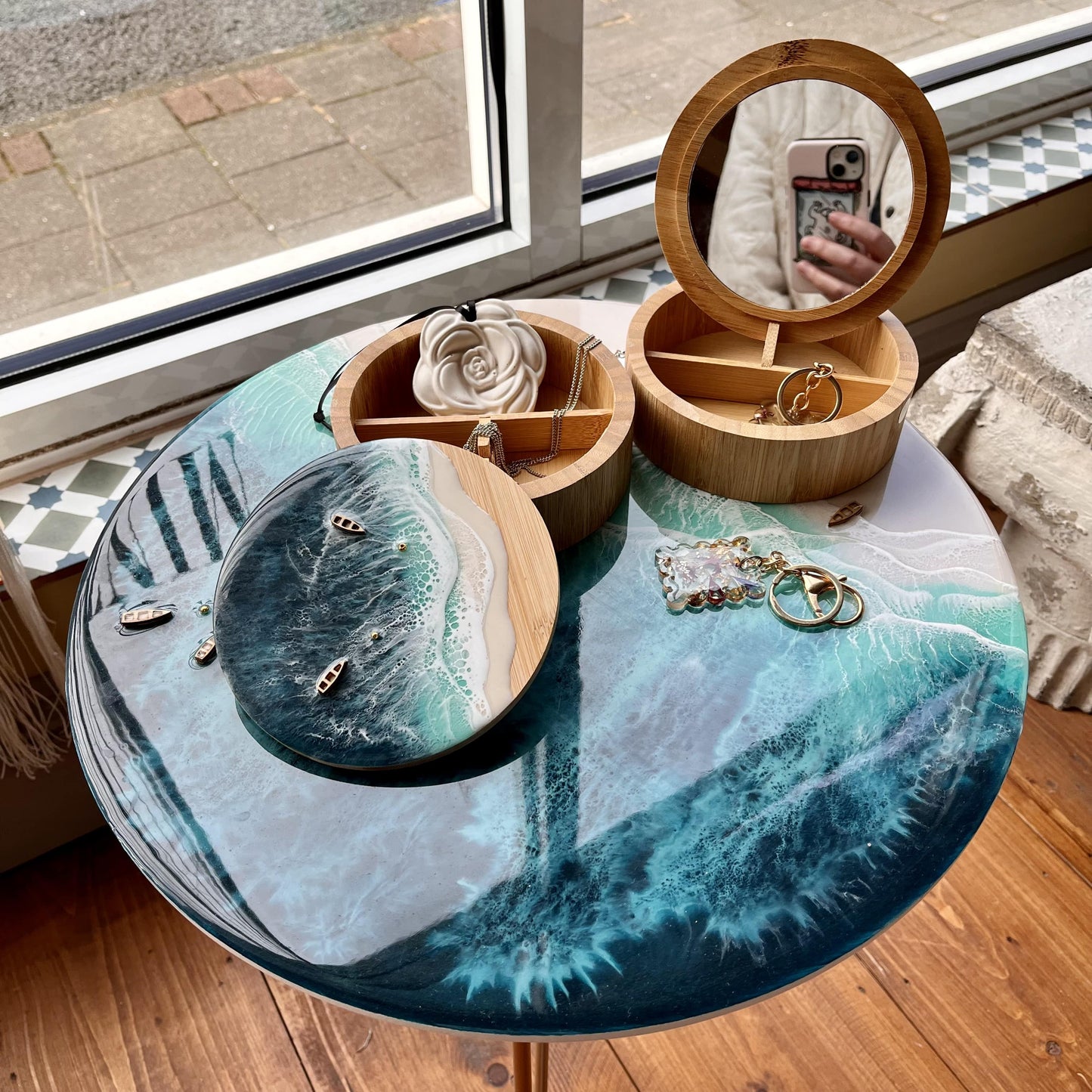 Wooden jewelry box with mirror on a round table with blue and green design.