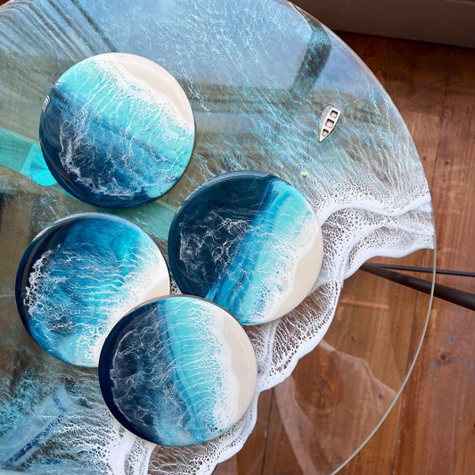 Set of four blue and white marbled coasters on a glass table.