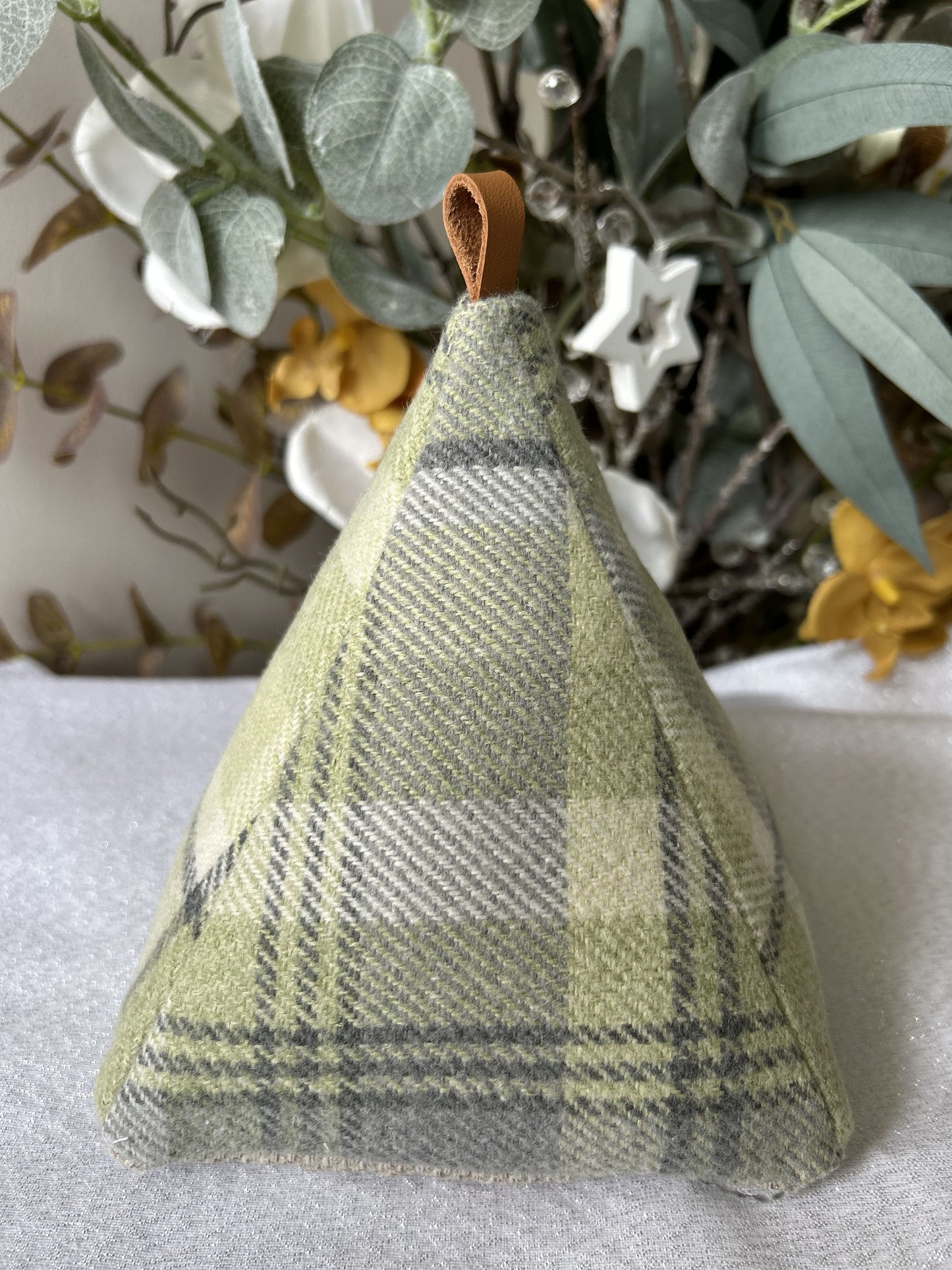Green handmade Welsh wool pyramid doorstop with looped leather handle, soft-touch fabric, unique Welsh home accessory.