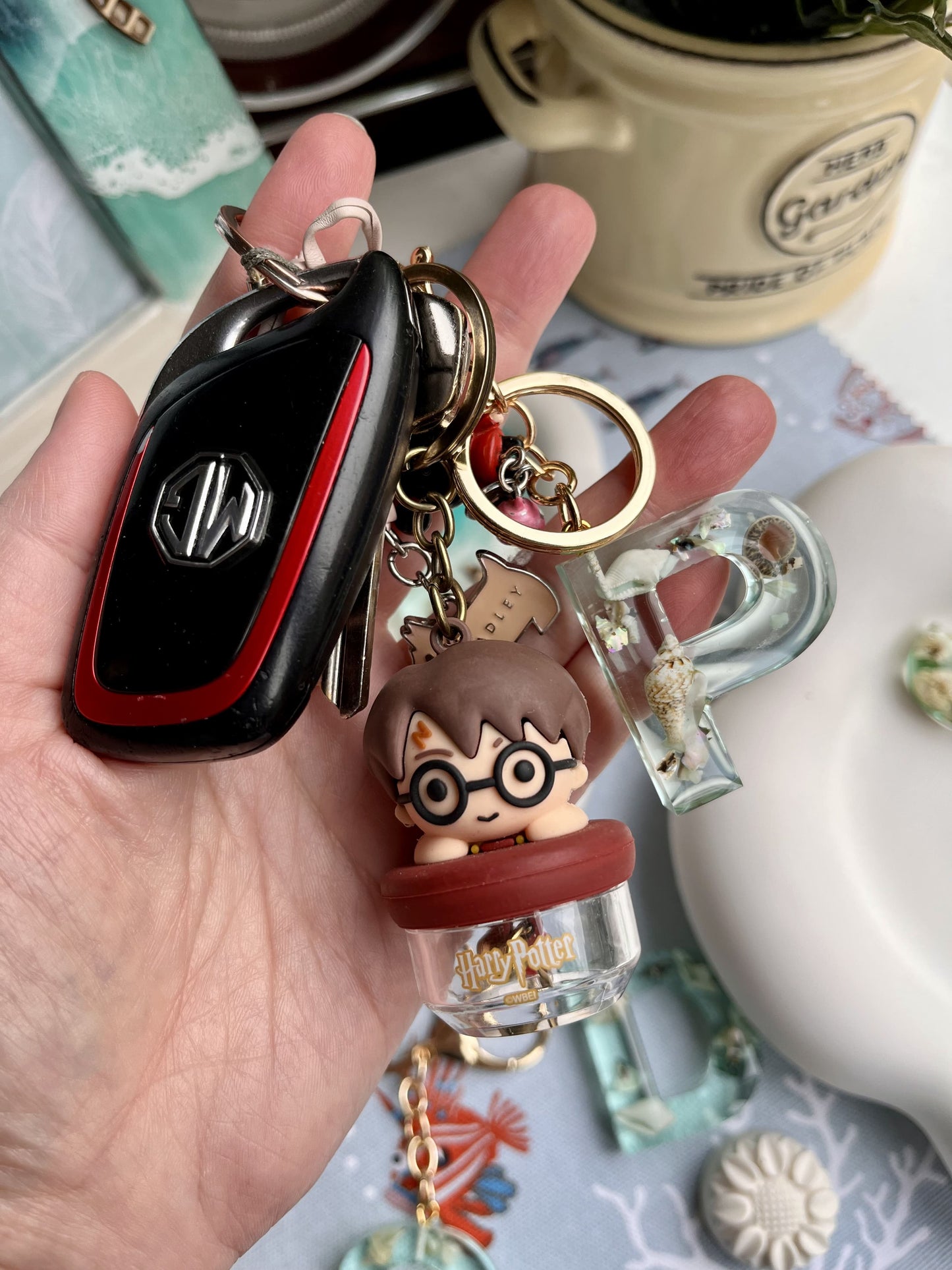 Hand holding a keychain with a small figurine and other charms on a decorative surface.