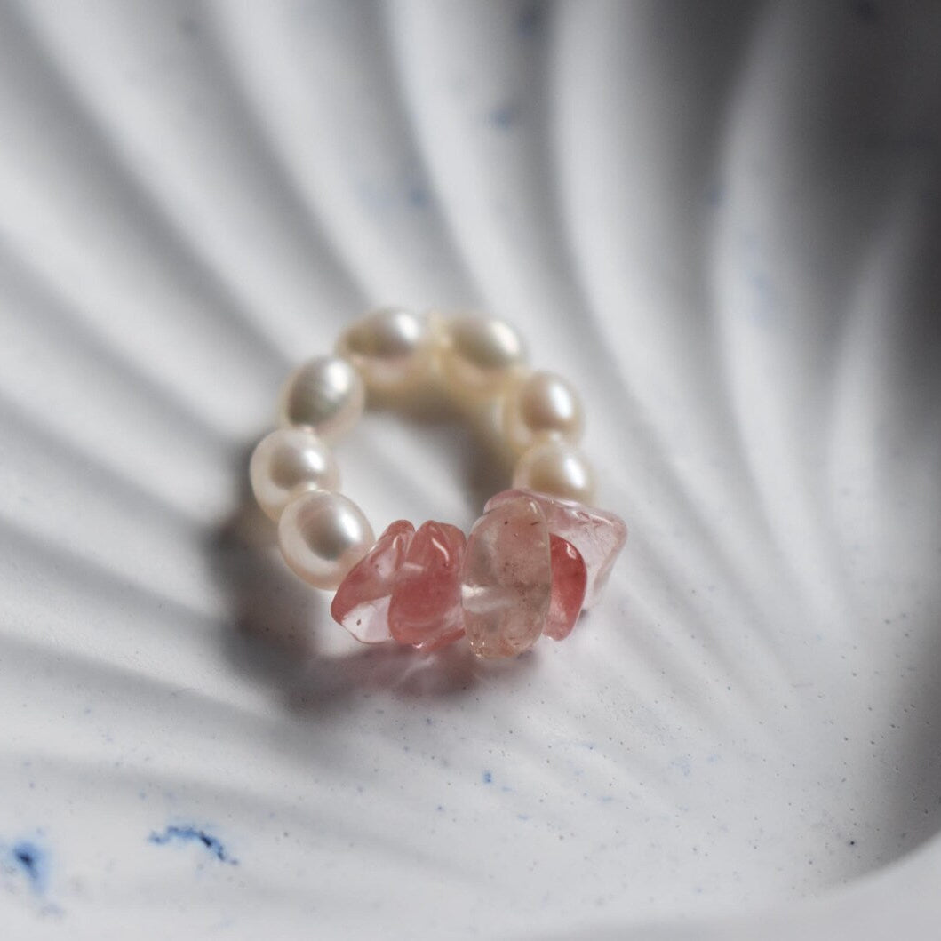 Ring with pearls and pink stones on a textured surface, handmade by independent jewellery maker in Wales.
