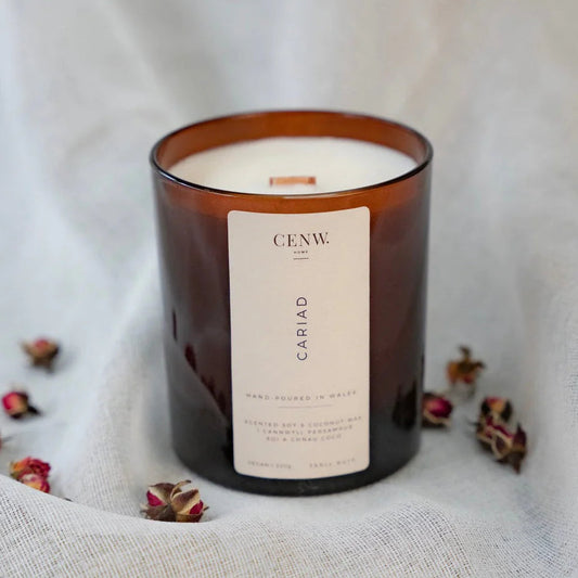 Cariad peony and suede soy candle hand-poured in Wales, on a white fabric background