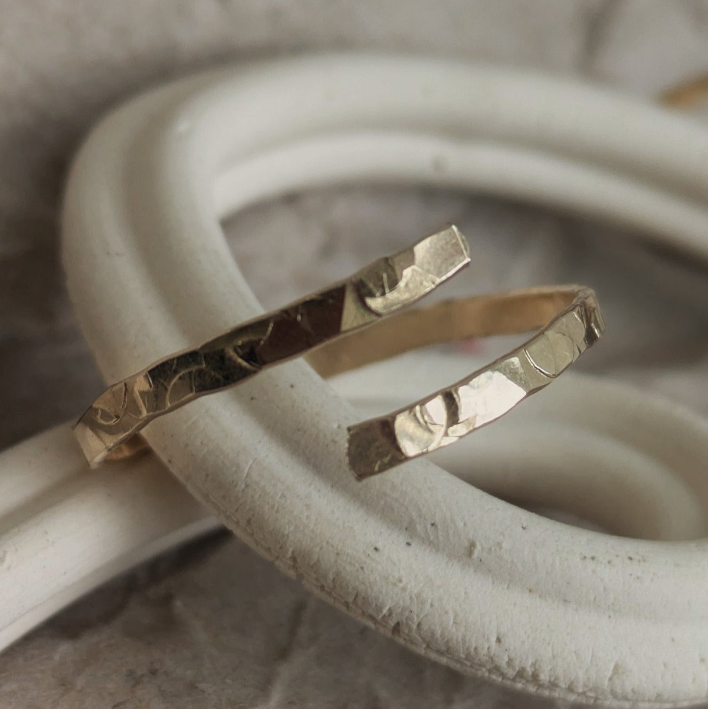 Hammered adjustable gold ring, sat on a ceramic curved dish