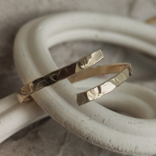 Hammered adjustable gold ring, sat on a ceramic curved dish