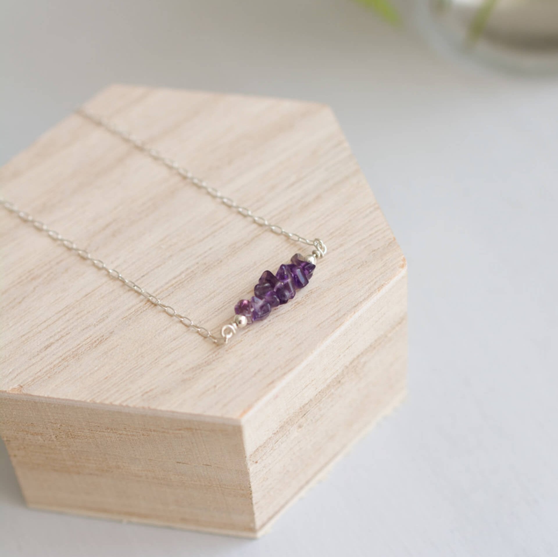 Purple handmade Amethyst Crystals Necklace on silver chain, sat on wooden box

