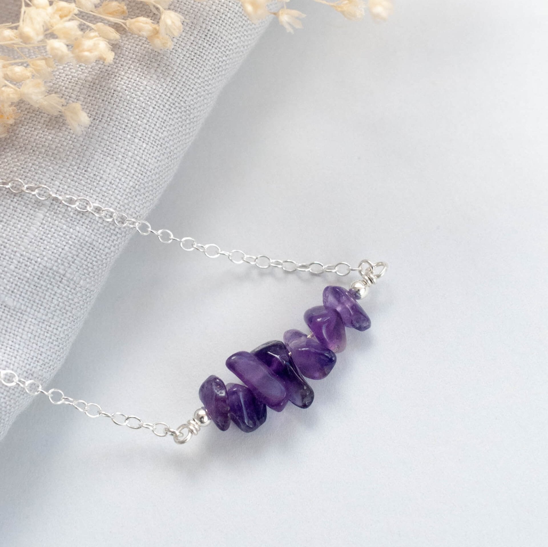 Purple handmade Amethyst Crystals Necklace on silver chain, sat on grey background