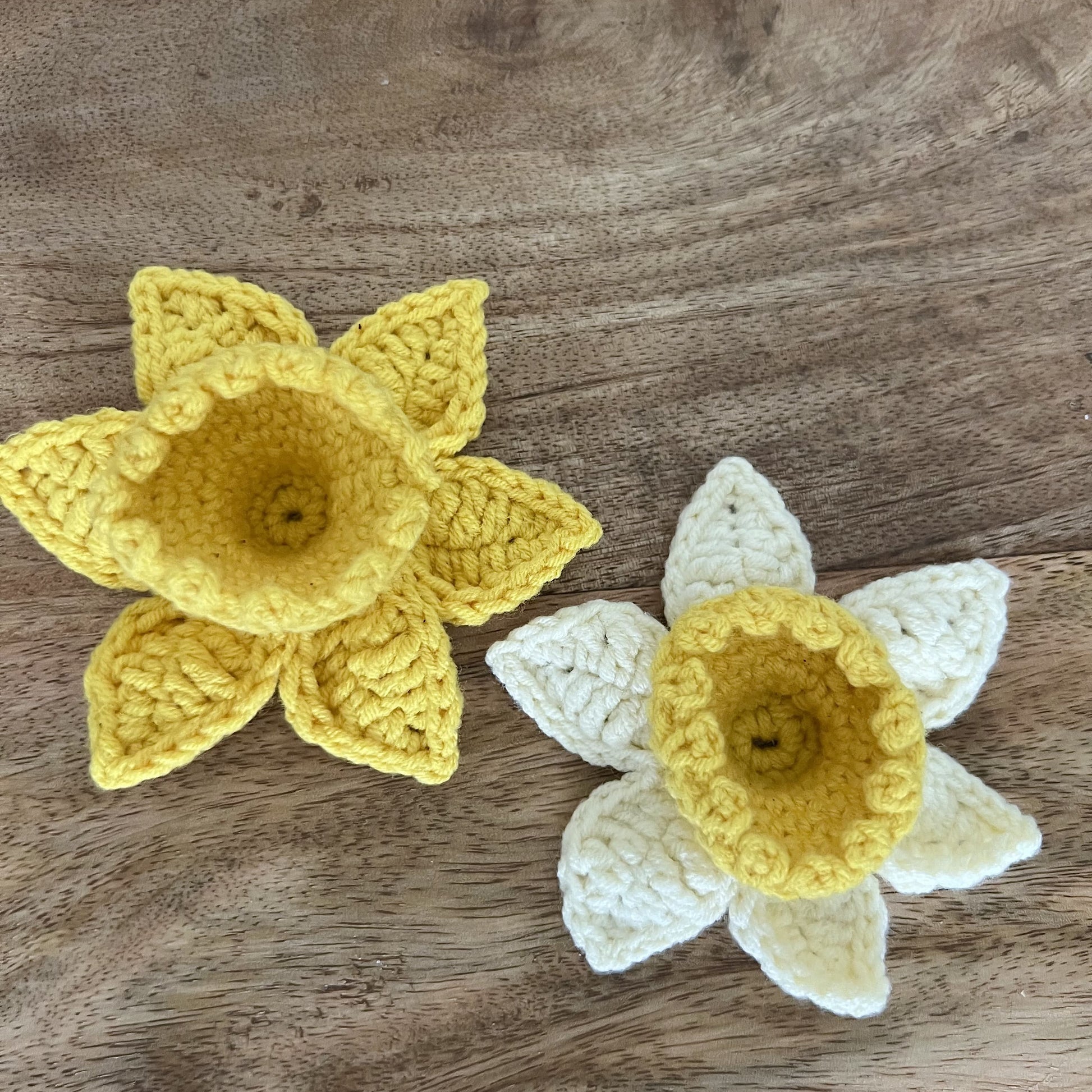 Two crocheted Welsh daffodil badges, one yellow and one white, displayed for gift-giving, St David’s Day, or Welsh keepsake.
