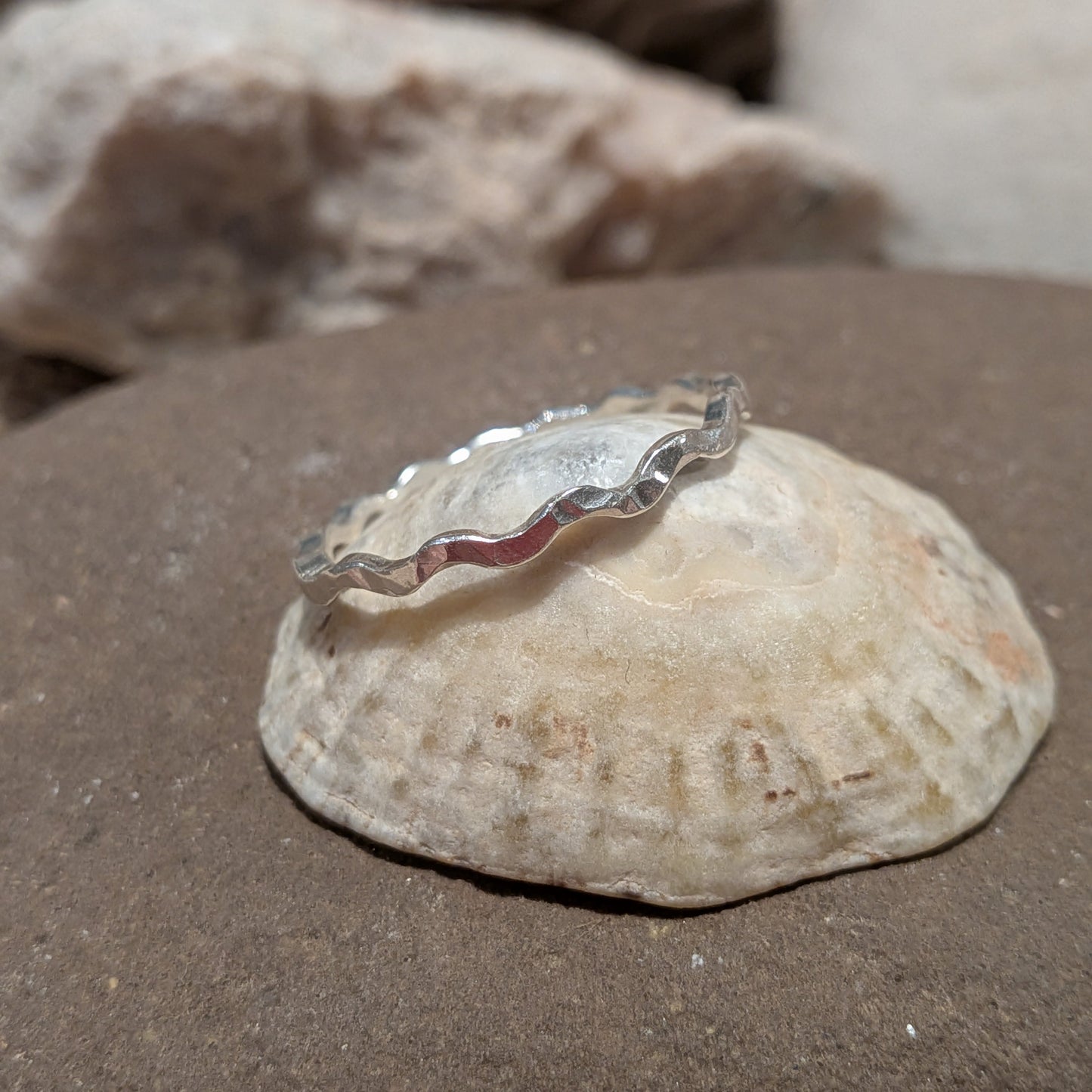 Handmade recycled silver wavy ring Tonnog with hammered texture, made in Wales. Silver ring sat on seashell, inspired by the sea.