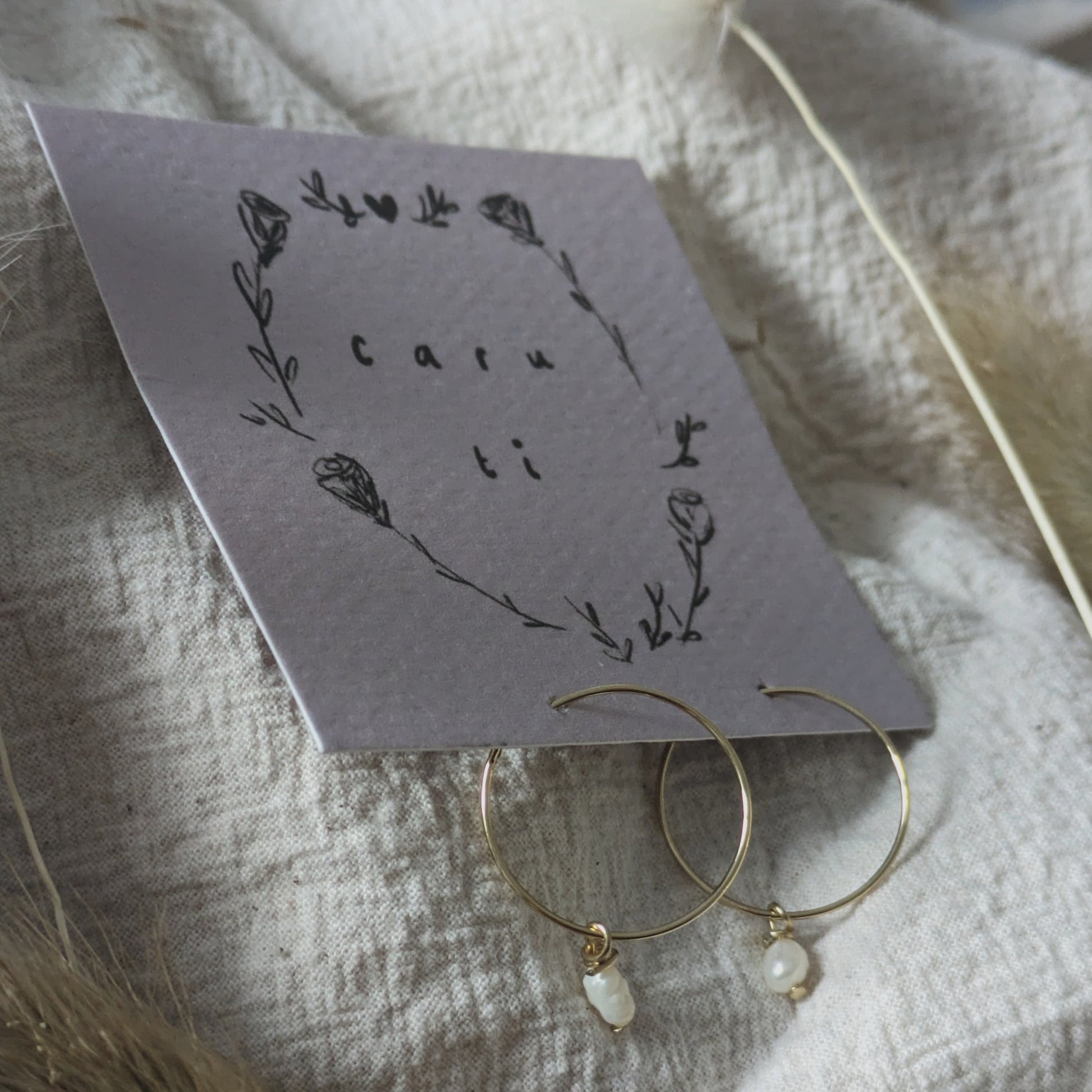 Handmade pearl hoops clipped onto a card backing featuring the Welsh words 'Caru Ti'