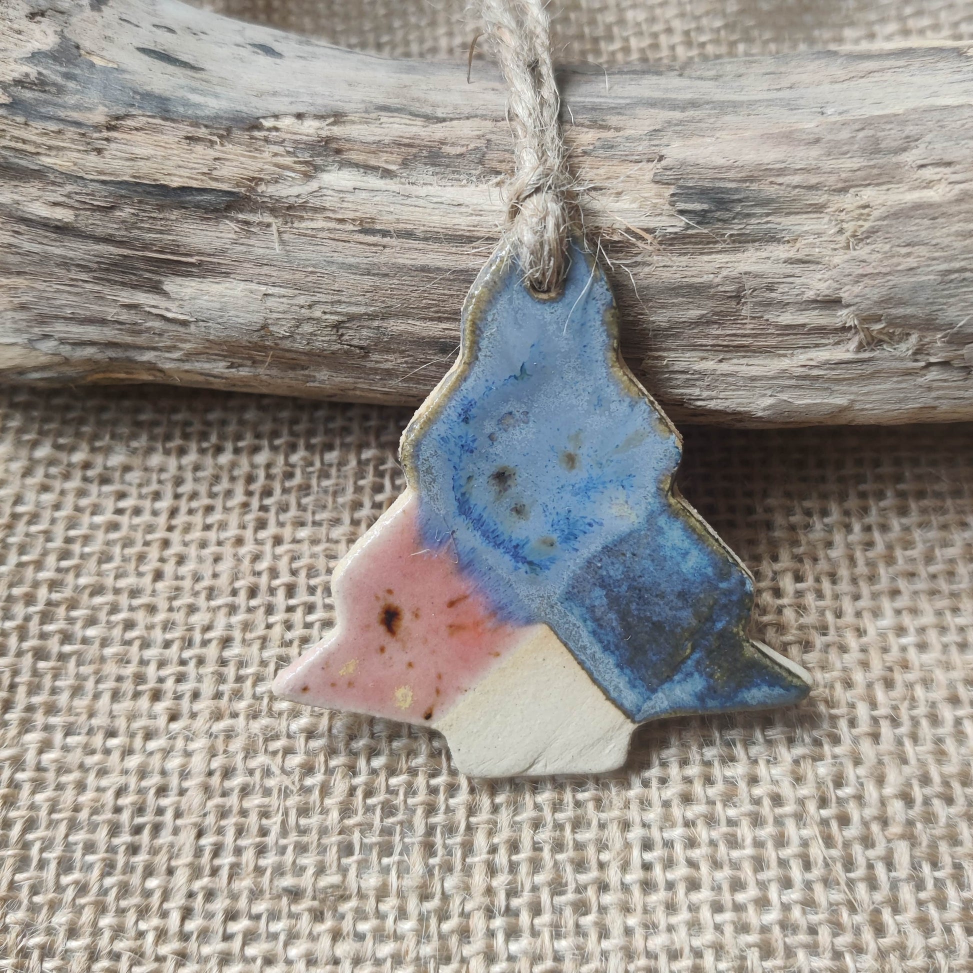 Decorative ceramic Christmas tree ornament with blue and pink colours on a rustic background. perfect handmade gift for christmas.