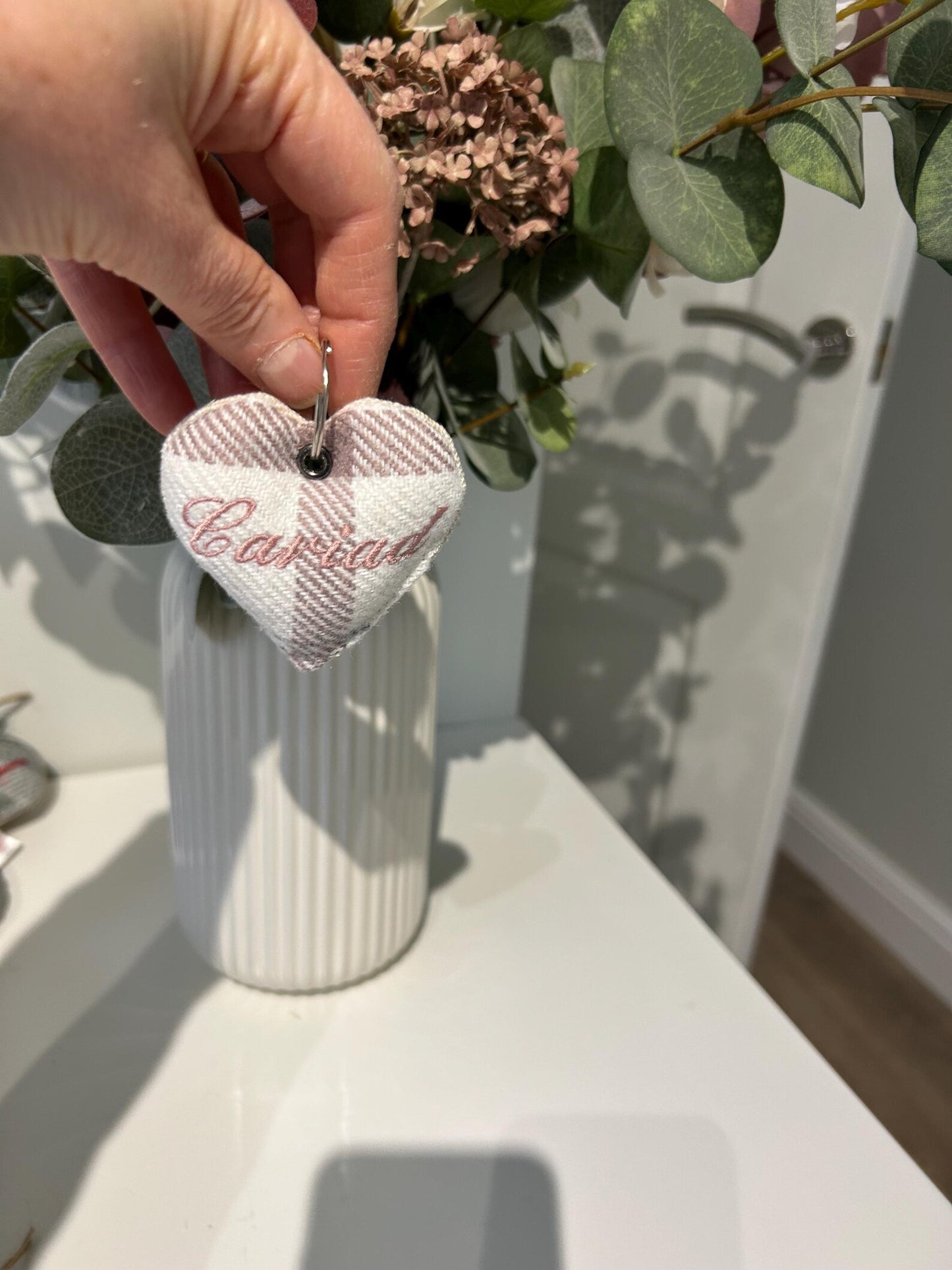 Handmade heart-shaped keyring with 'Casablanca' text held by a hand in front of a white vase with greenery. unique Welsh textile gift accessory for birthdays, Christmas, weddings