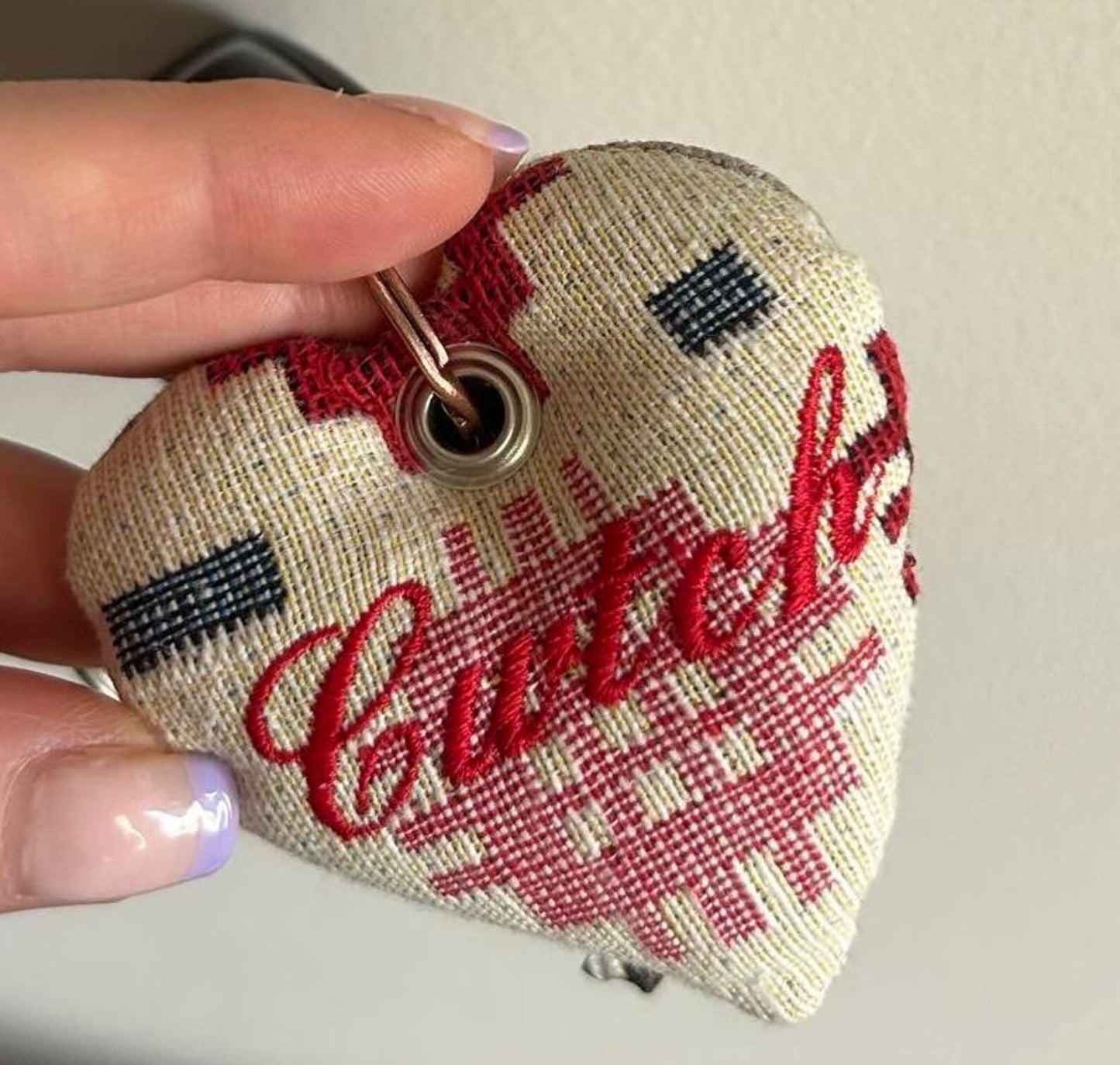 Handmade heart-shaped fabric keyring with 'Cwtch' text and checkered pattern held by a hand. unique Welsh textile gift accessory for birthdays, Christmas, weddings