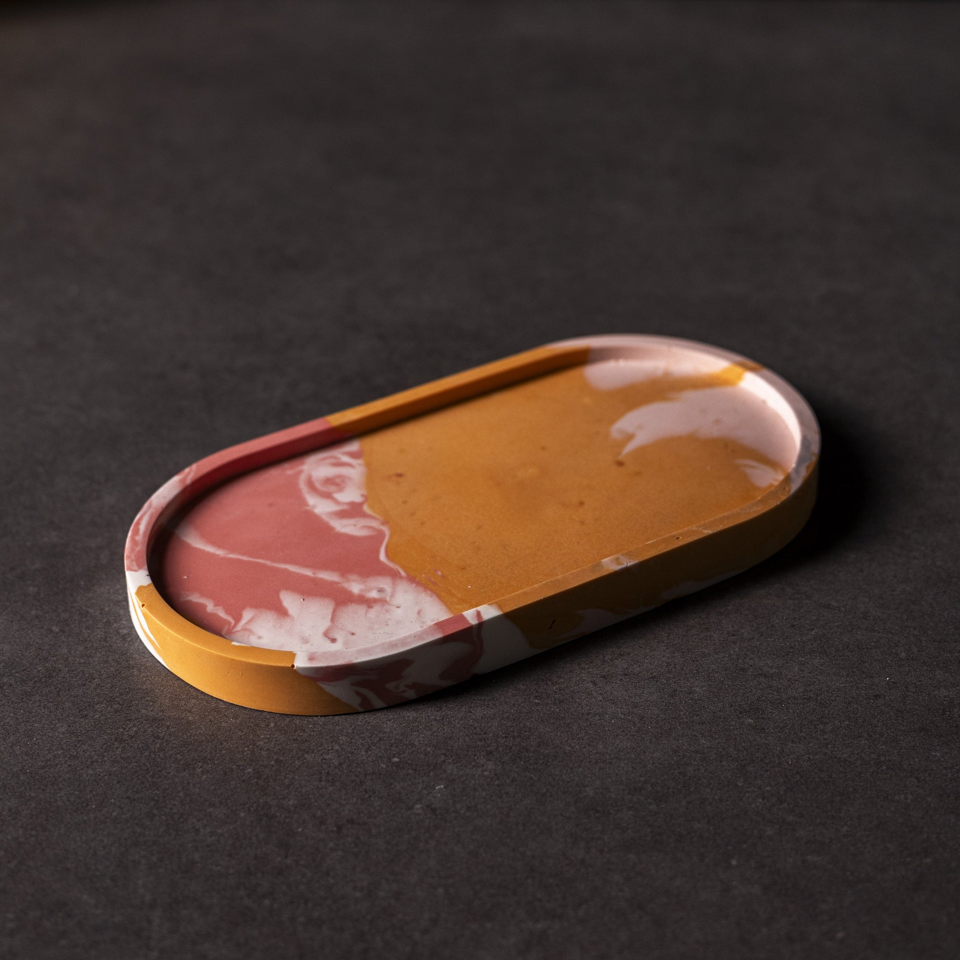 Close up of oval pink/red/orange Jesmonite trinket tray, handcrafted in Wales, perfect for storing jewellery or small items as a gift