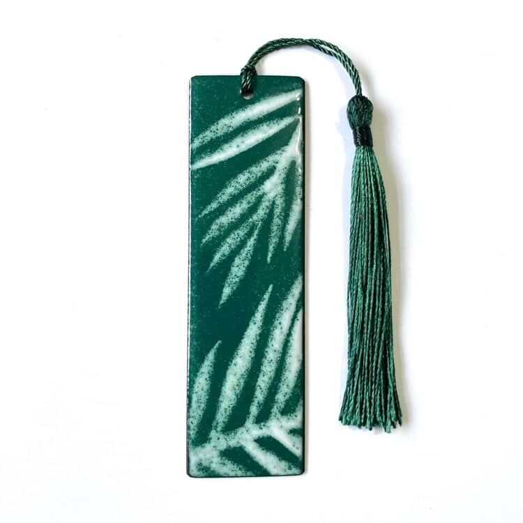 Green leaf patterned bookmark with a tassel on a white background. Made from enamelled copper, handcrafted in Wales.