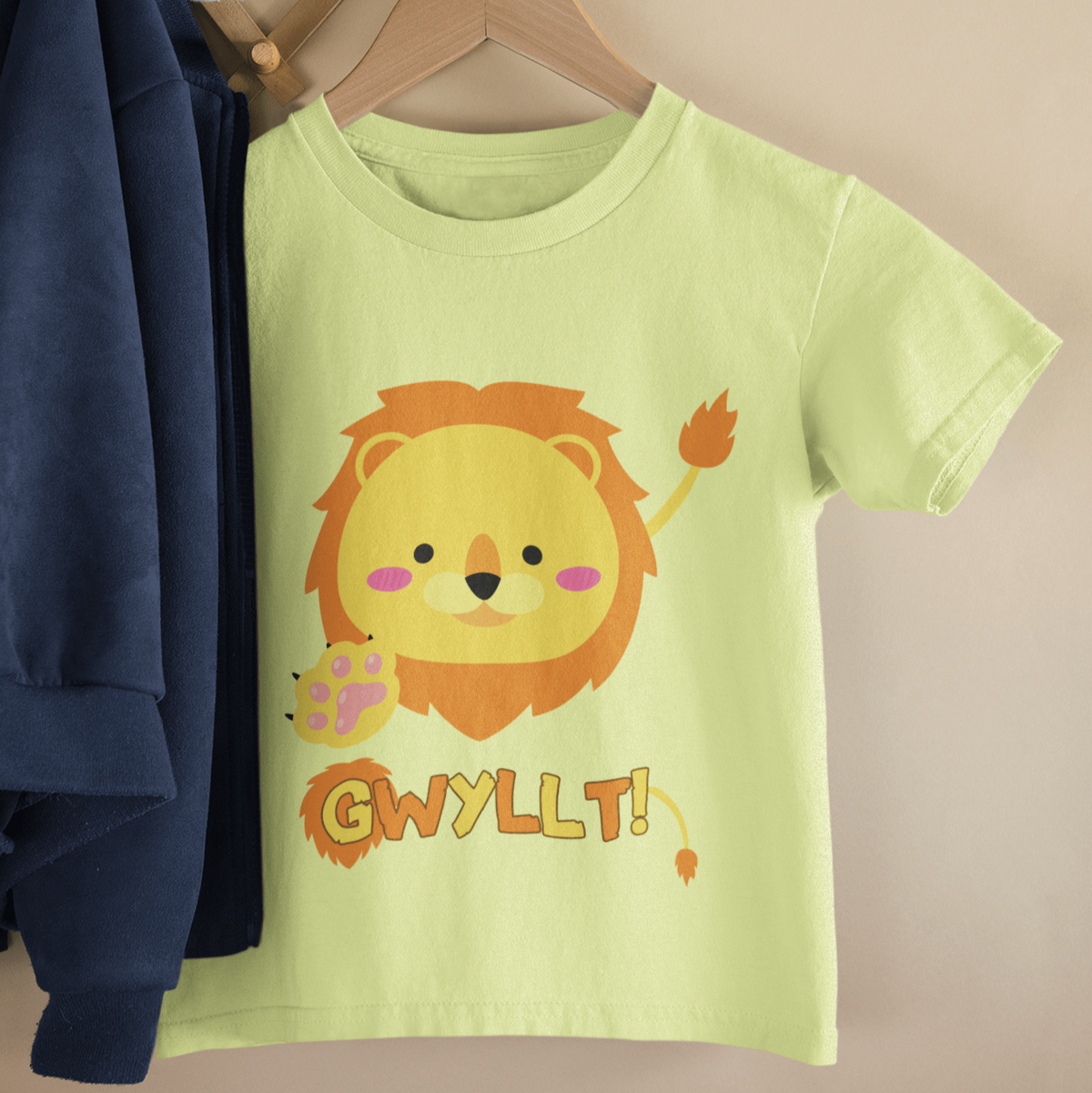 A kids' t-shirt featuring an illustrated lion design, hung up on a wooden hanger. Perfect for new baby and toddler gifts, birthdays, school days, playtime or thoughtful Welsh gifts for children.