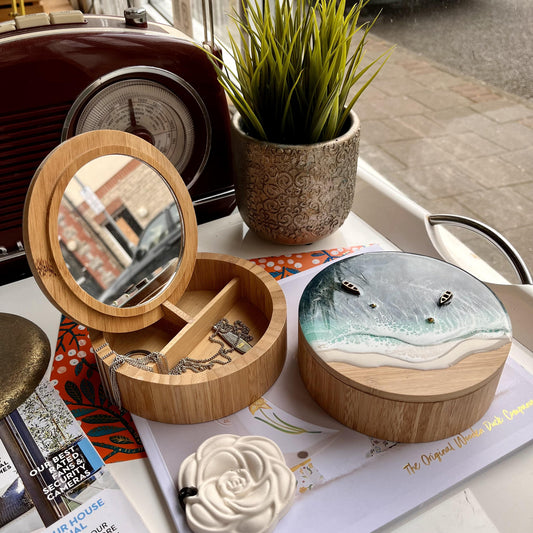 Wooden jewelry box with mirror and sea-themed lid on a magazine