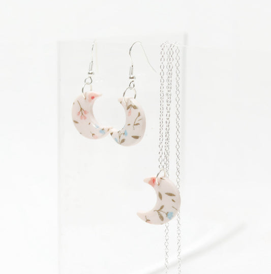 Small white and pink crescent necklace featuring floral designs made of polymer clay and resin. Ideal for gifts for her, lovers of bold jewellery, floral prints and handmade artisan gifts.