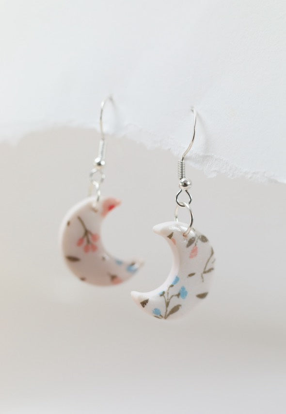 Small white and pink crescent necklace featuring floral designs made of polymer clay and resin. Ideal for gifts for her, lovers of bold jewellery, floral prints and handmade artisan gifts.