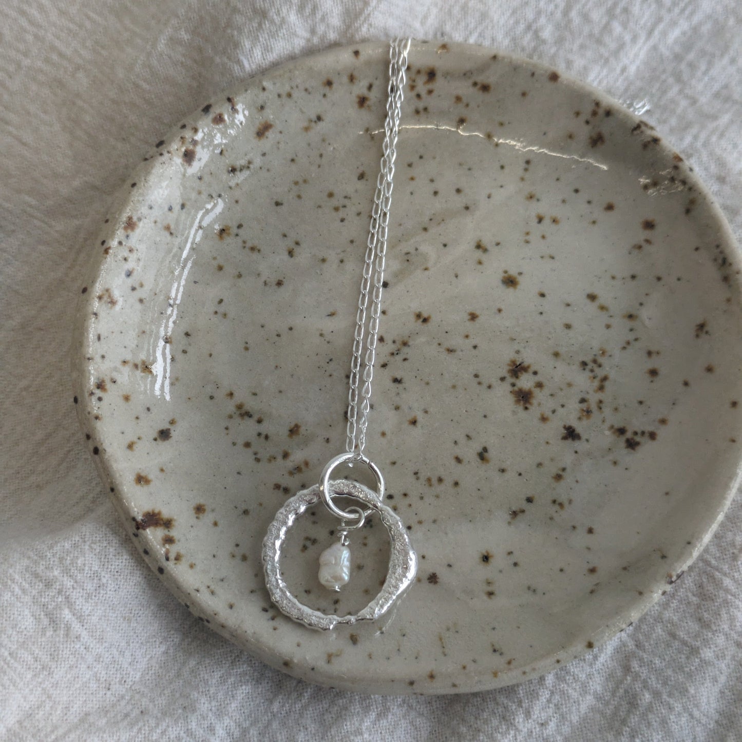 Handmade necklace sitting on a ceramic trinket tray