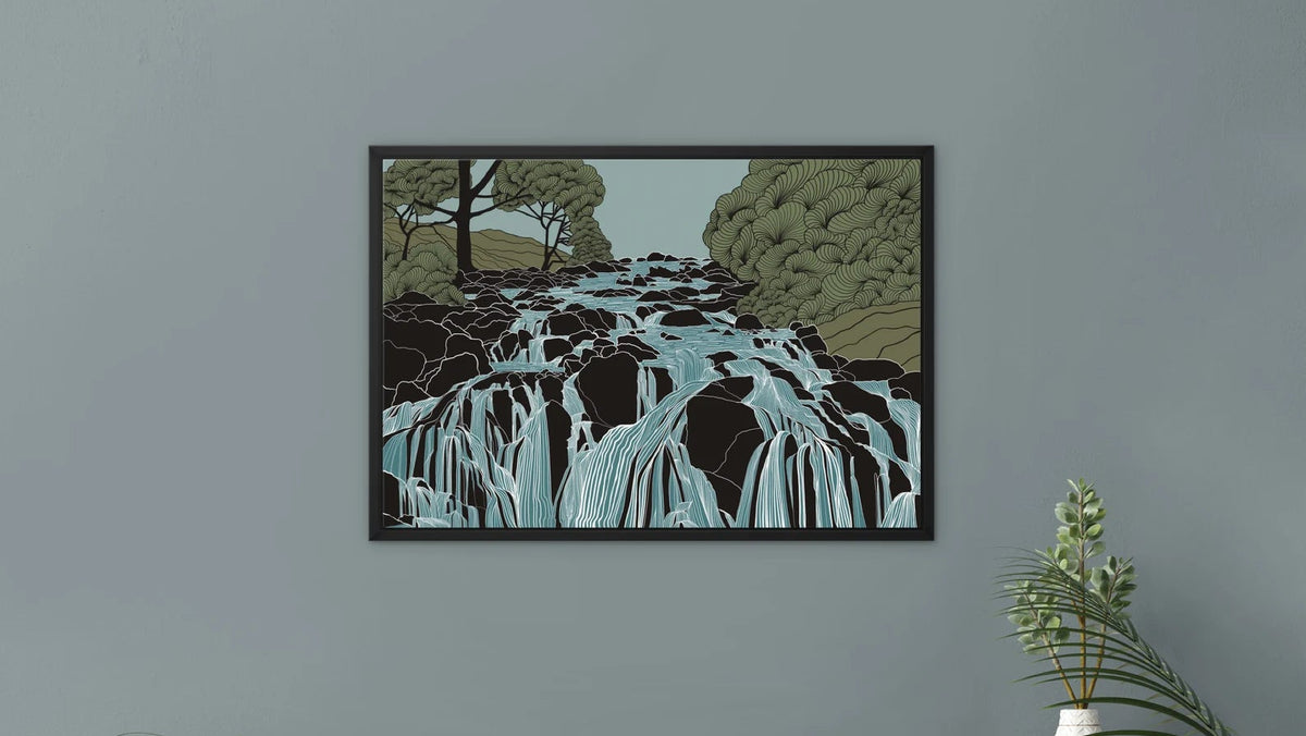 A framed art print depicting a waterfall landscape in black, green, and light blue tones, displayed on a gray wall above a light pink cabinet with decorative plants and books.