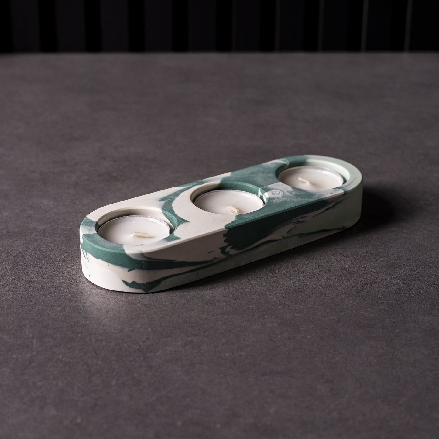 Marble triple patterned candle holder on a dark surface with a black background, made in Cardiff, Wales.