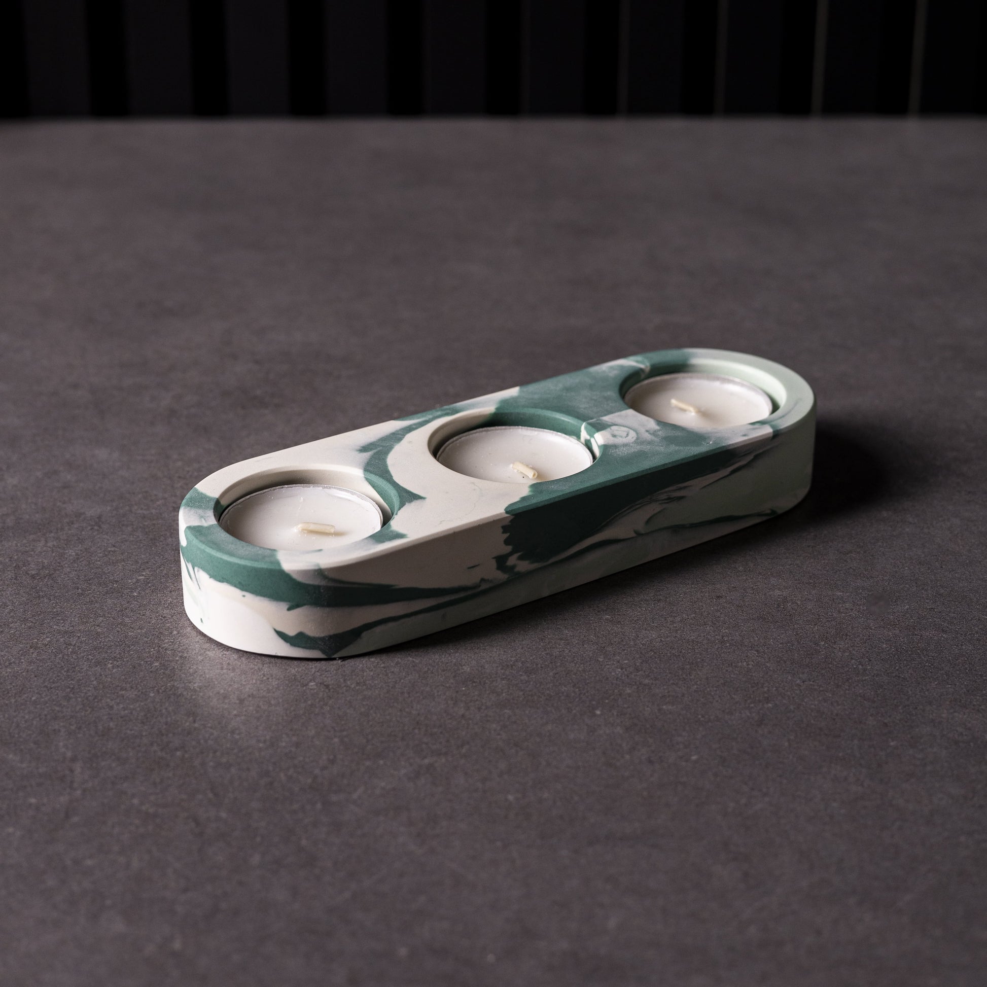 Marble triple patterned candle holder on a dark surface with a black background, made in Cardiff, Wales.