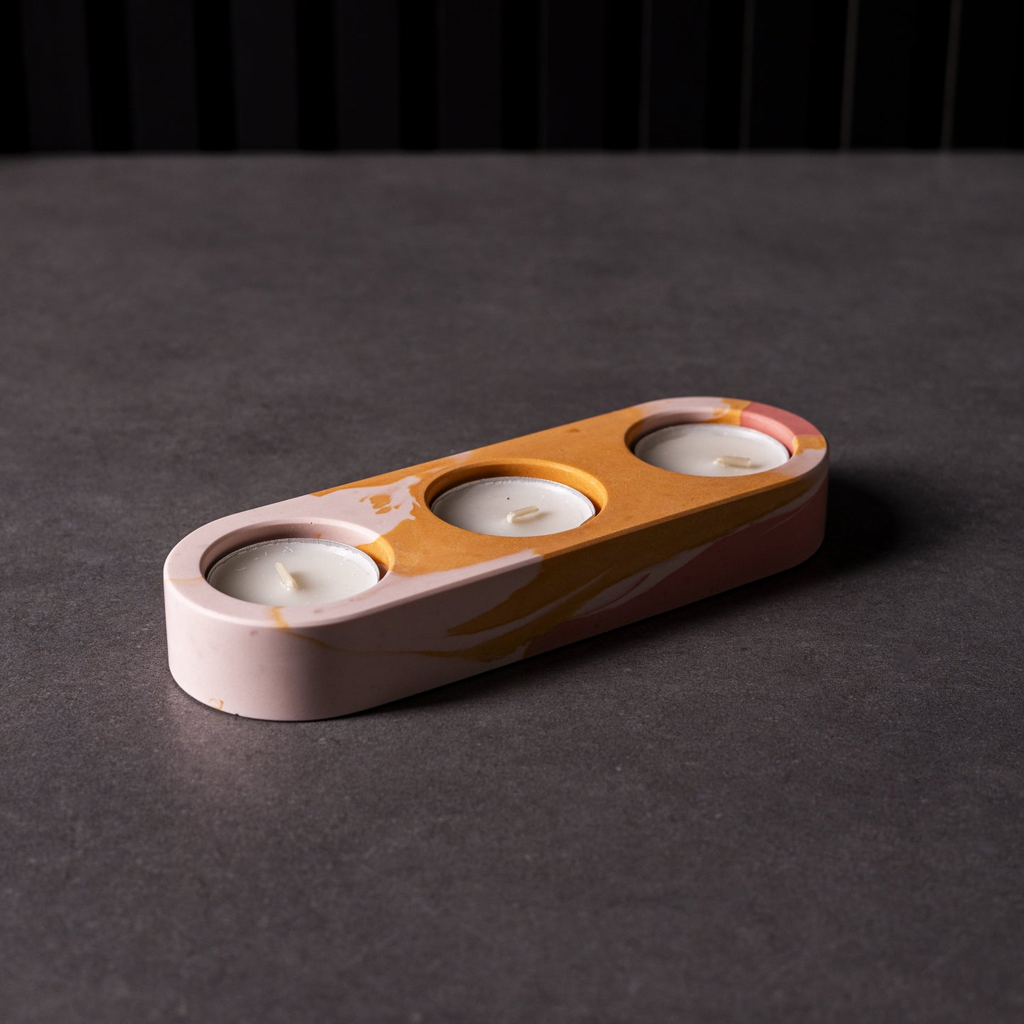 Ceramic candle holder with three small candles on a dark surface. Perfect gift for home interior lovers.