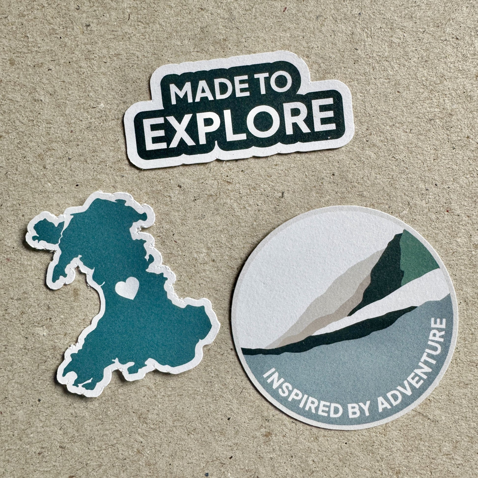 Set of three eco white vinyl adventure stickers – mountain, explore text, and Wales map designs