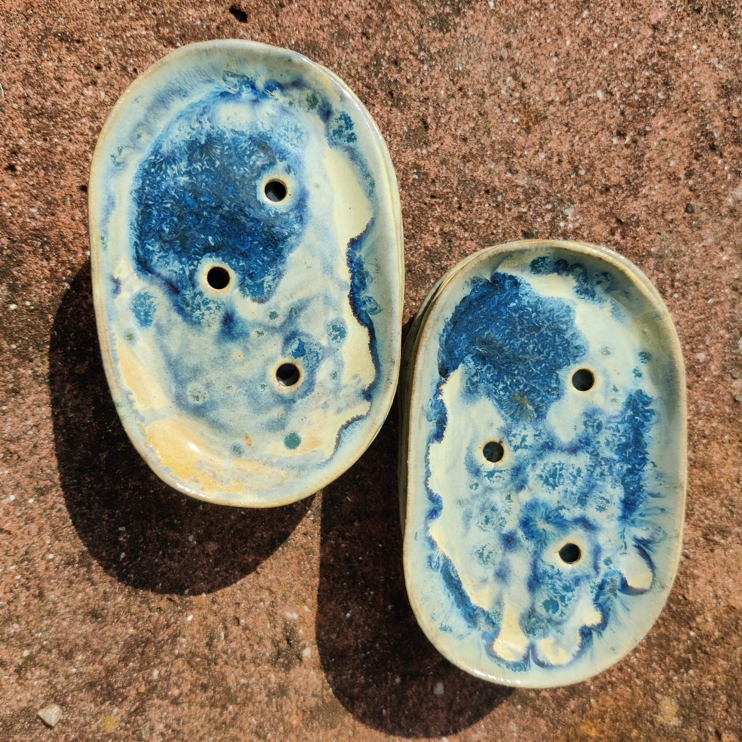 Two ceramic oval dishes with blue and white glaze on a textured brown surface