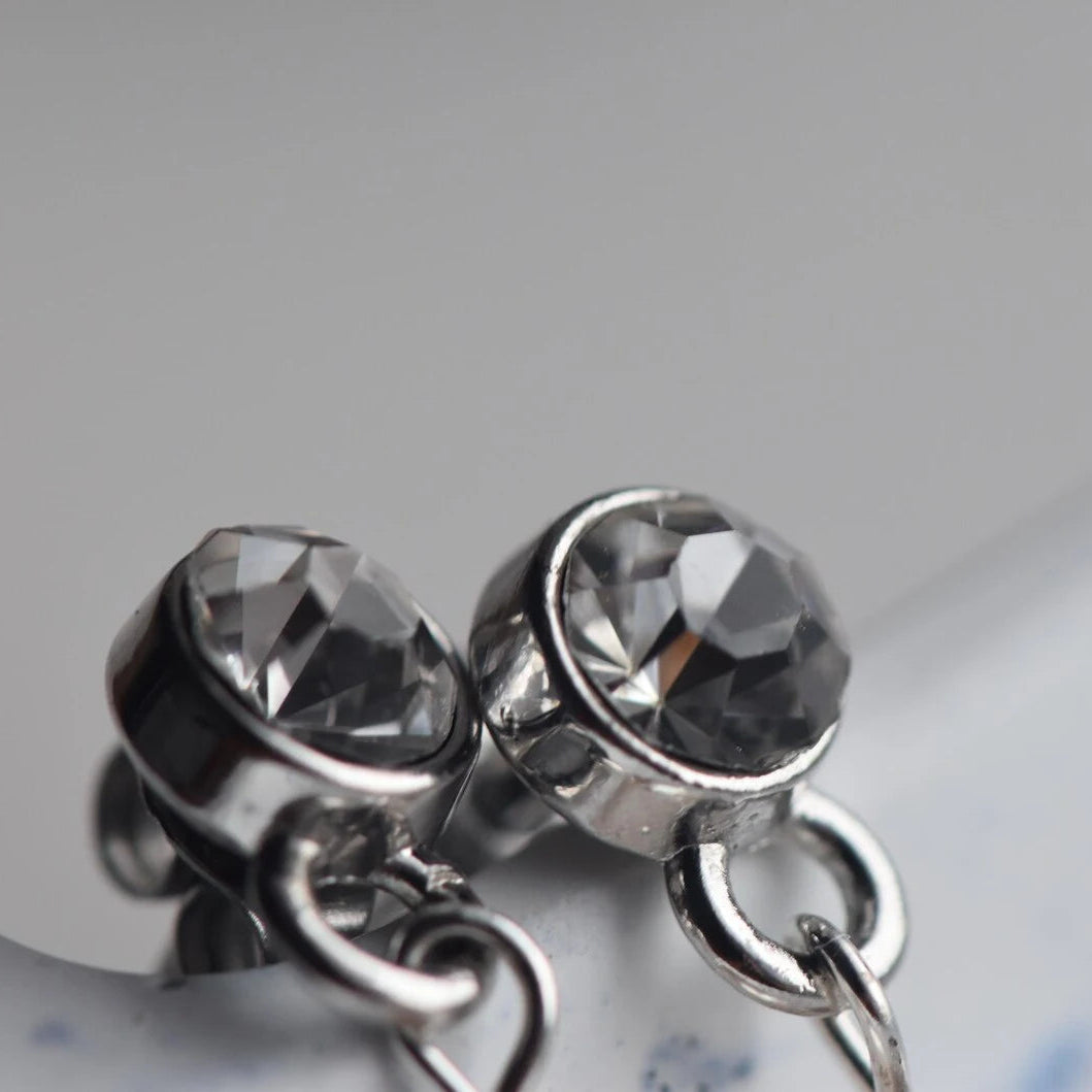 Close-up of silver earrings with clear gemstones on a blurred background