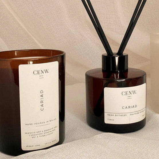 Diffuser and candle on a textured surface. Floral soy wax candle with wooden wick, romantic gift idea.