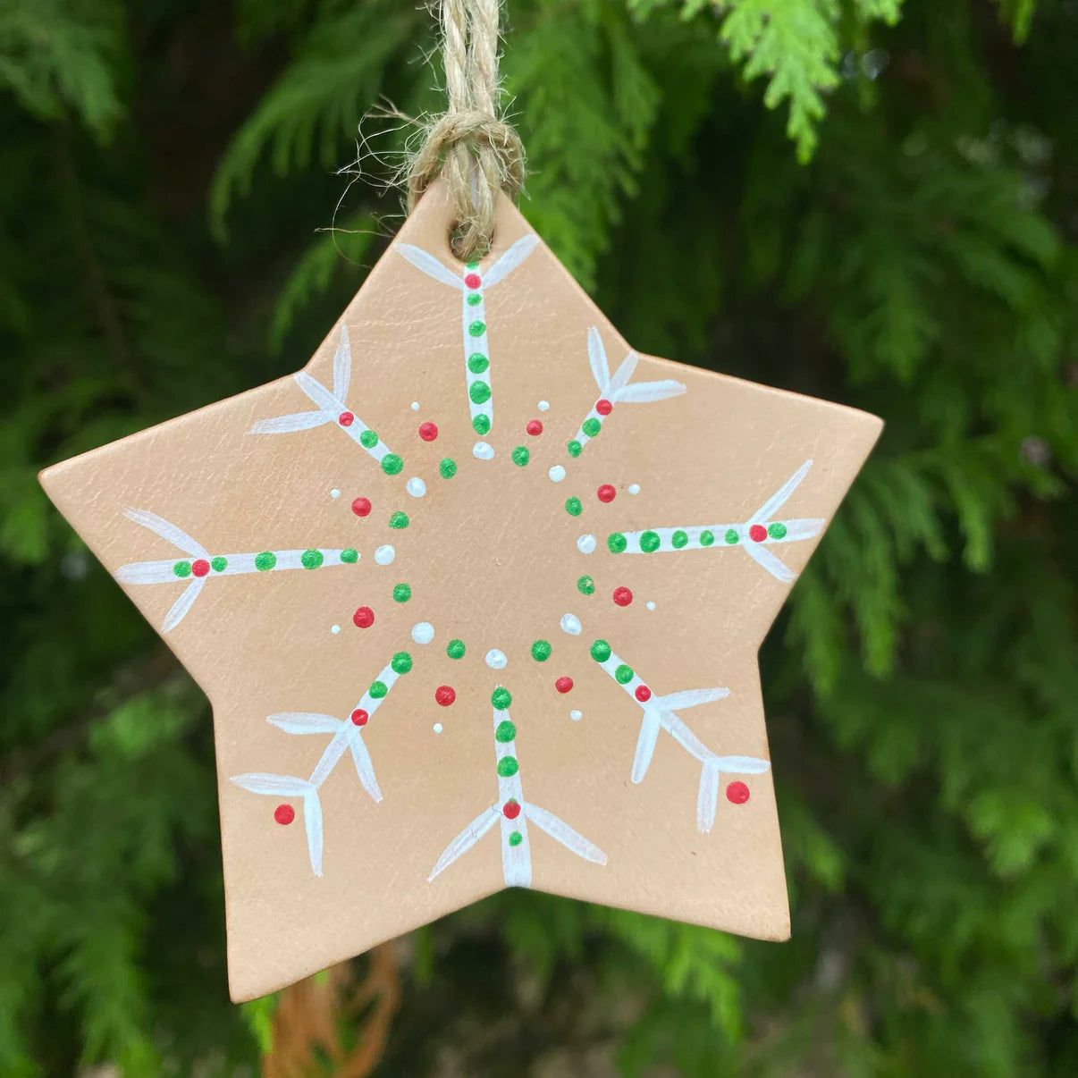Hand-painted leather snowflake Christmas decoration in red, white, and green.