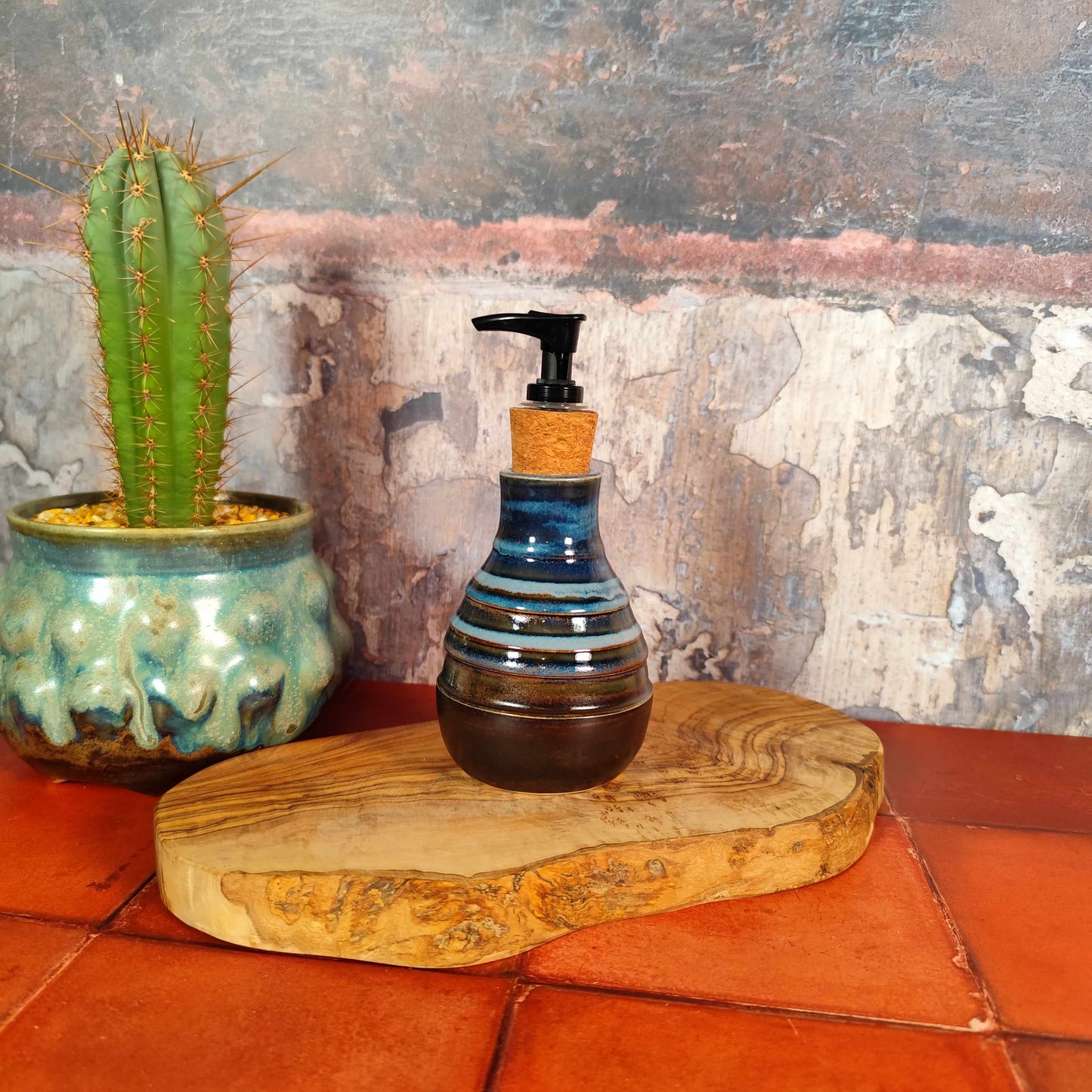 Decorative bottle with pump on a wooden board next to a cactus plant against a textured wall, supporting Welsh makers