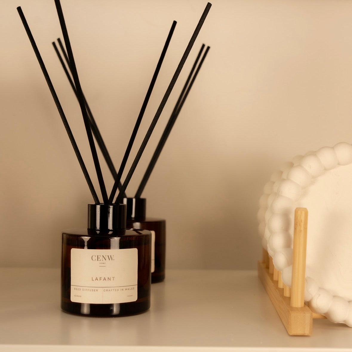 Diffuser on a shelf next to a wooden stand. Home fragrance diffuser for bedrooms and living spaces.
