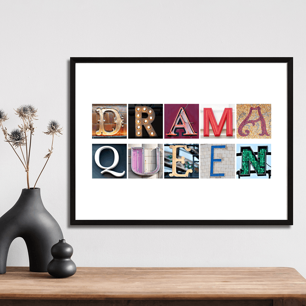 Framed artwork with 'Drama Queen' typography fine art print in colourful letters on a wall above a wooden surface. Made in Wales.