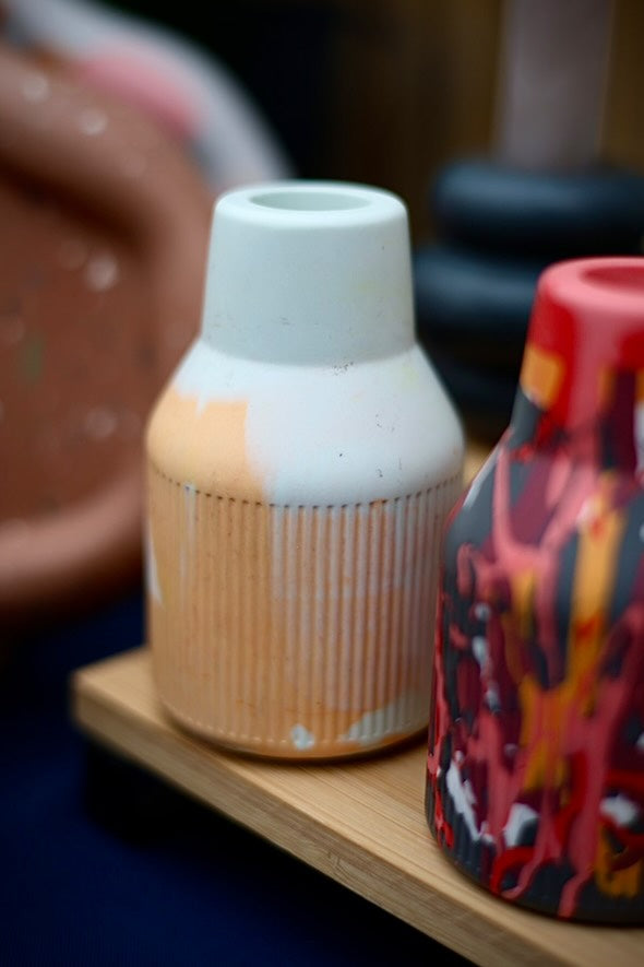 A table showcasing one small ribbed jesomite vase in coral and pale blue colours. Perfect as a gift or to add to your home.