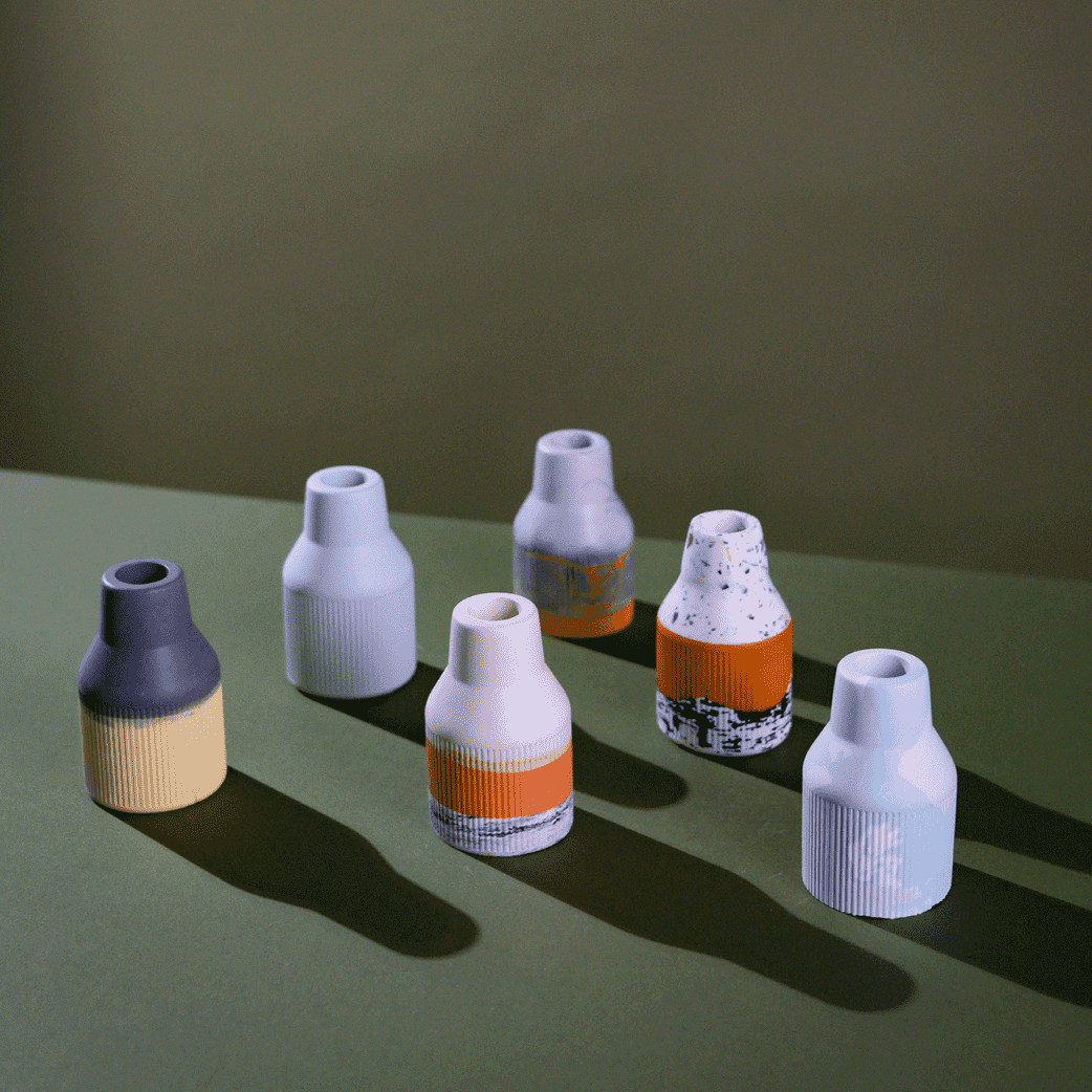 A table set with an assortment of vases, showcasing small ribbed jesomite vases in vibrant colours. Perfect as a gift or to add to your home.