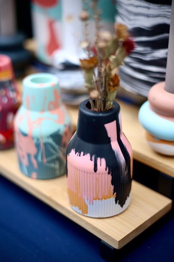 A table showcasing one small ribbed jesomite vase in vibrant colours pink black and orange. Perfect as a gift or to add to your home.