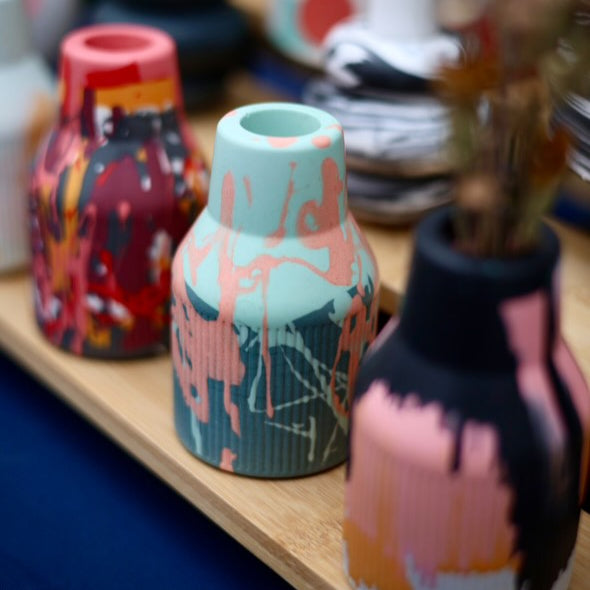 A table set with an assortment of vases, showcasing three small ribbed jesomite vases in vibrant colours. Perfect as a gift or to add to your home.