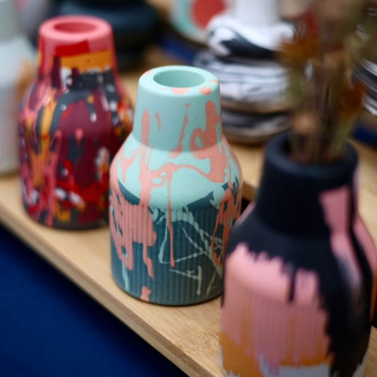 A table set with an assortment of vases, showcasing three small ribbed jesomite vases in vibrant colours. Perfect as a gift or to add to your home.