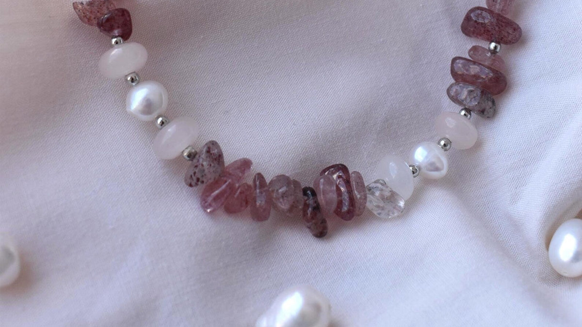 Necklace with pink beads and pearls on a white fabric background