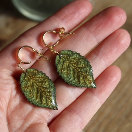 Gold plated hoop earrings with green resin leaf charms, handmade in Wales.
