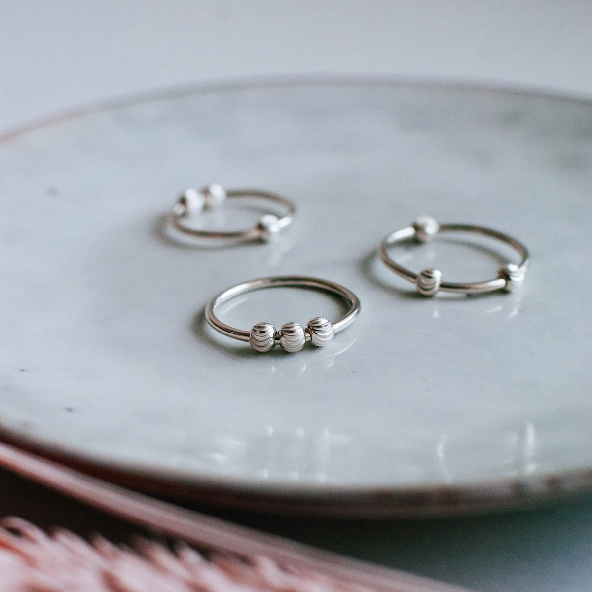 Handmade sterling silver spinner ring with tactile bead design, featuring three rings on a shiny marbled surface.