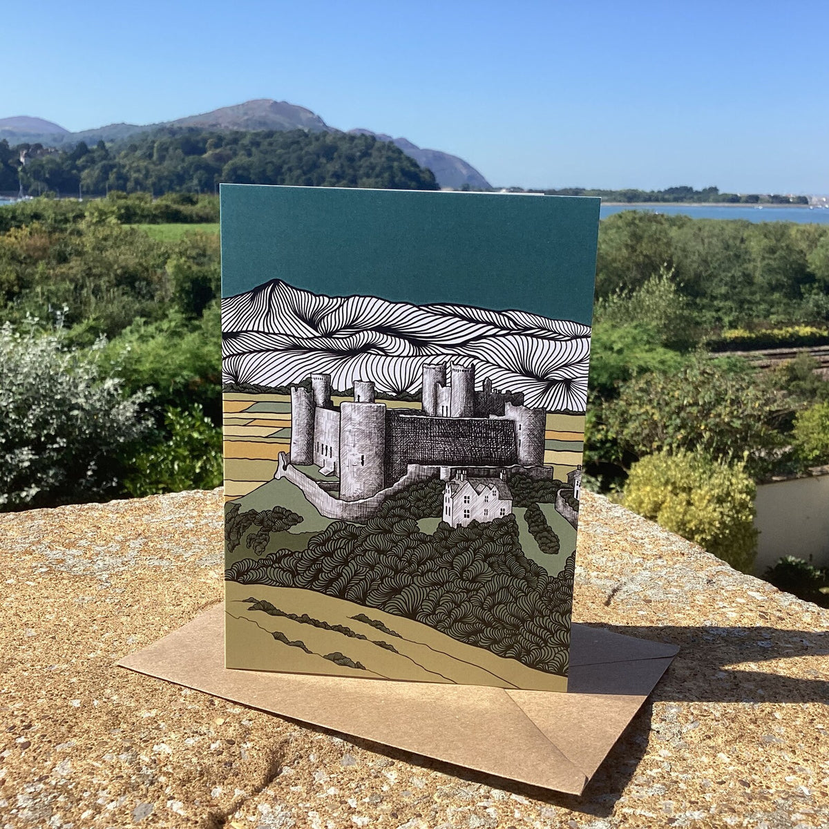 North Wales castle art greeting card with craft envelope, on a stone ledge with a scenic background