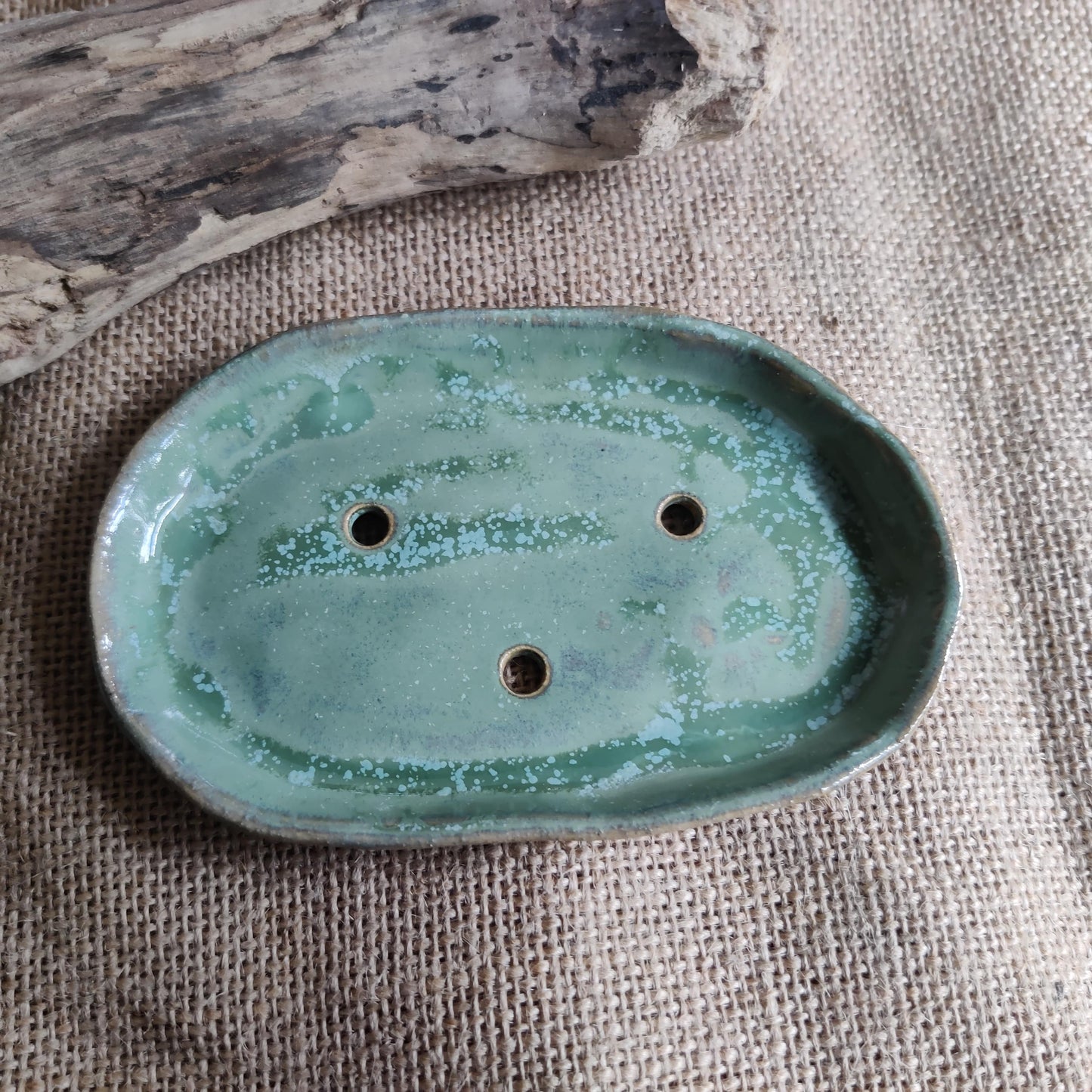 Green ceramic soap dish on a textured fabric background, locally made in Wales by talented small business.
