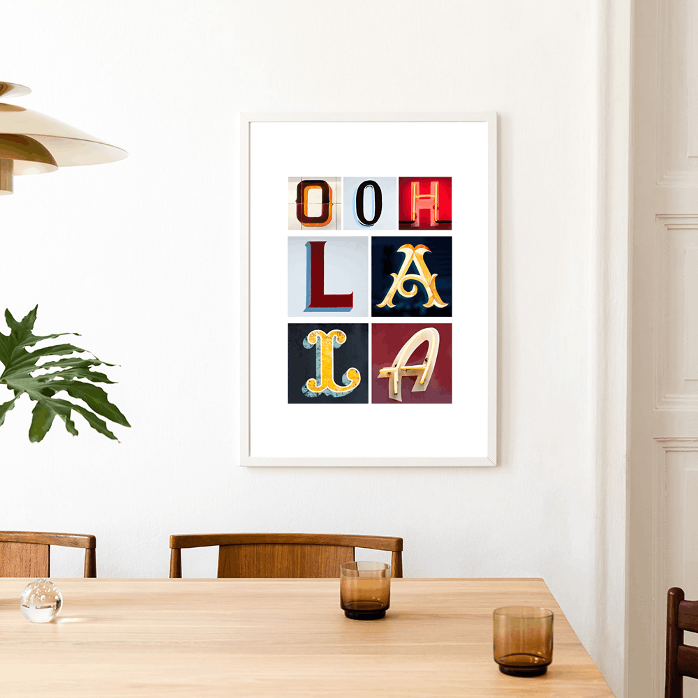 Framed artwork with colourful letters spelling 'Ooh La La' above a dining table. Ooh La La Paris typography fine art print with photographed letters.